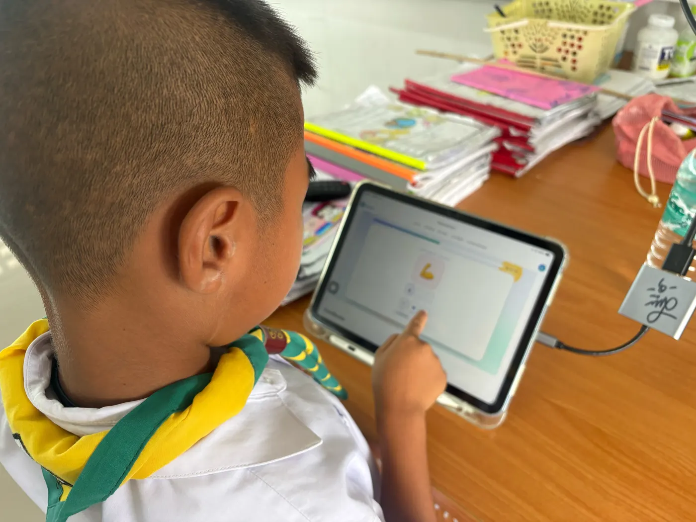 นักเรียนชายระดับประถมศึกษาแตะเลือกคำตอบบนแท็บเล็ต ในเกมคำศัพท์ภาษาอังกฤษหมวดอวัยวะร่างกายของคุณคูล